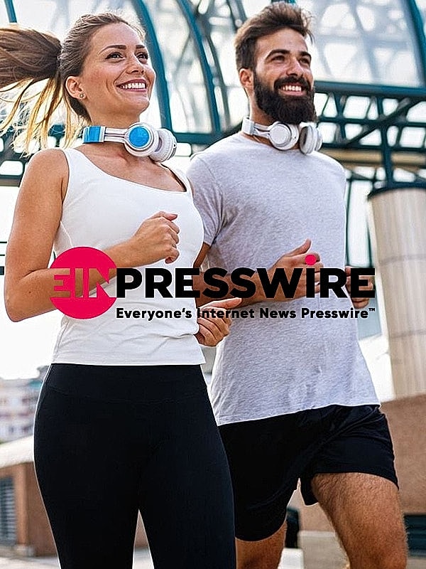 Couple jogging together wearing headphones outdoors.