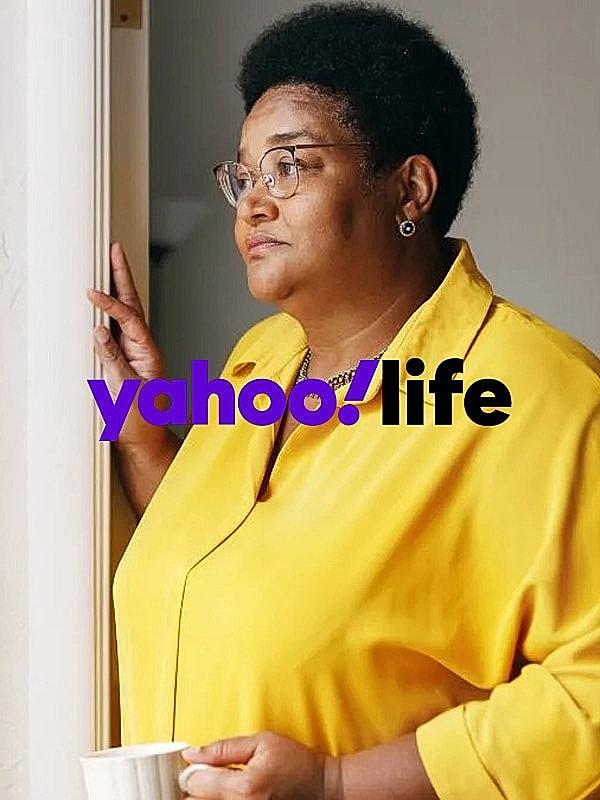 Woman in yellow shirt holding a cup.