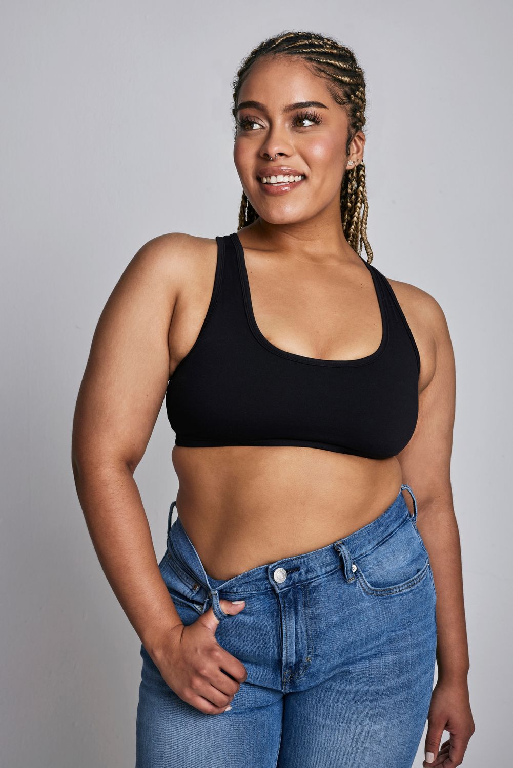 Smiling woman in sports bra and jeans.