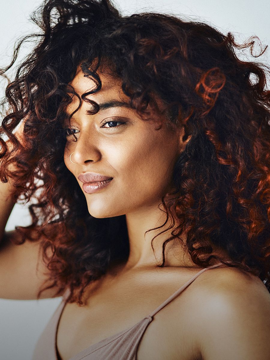 Woman with curly hair and glowing skin.