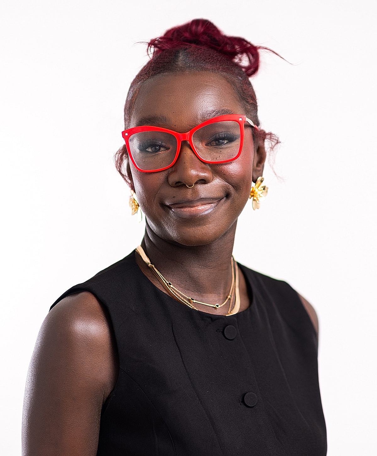 Smiling woman with red glasses and jewelry.