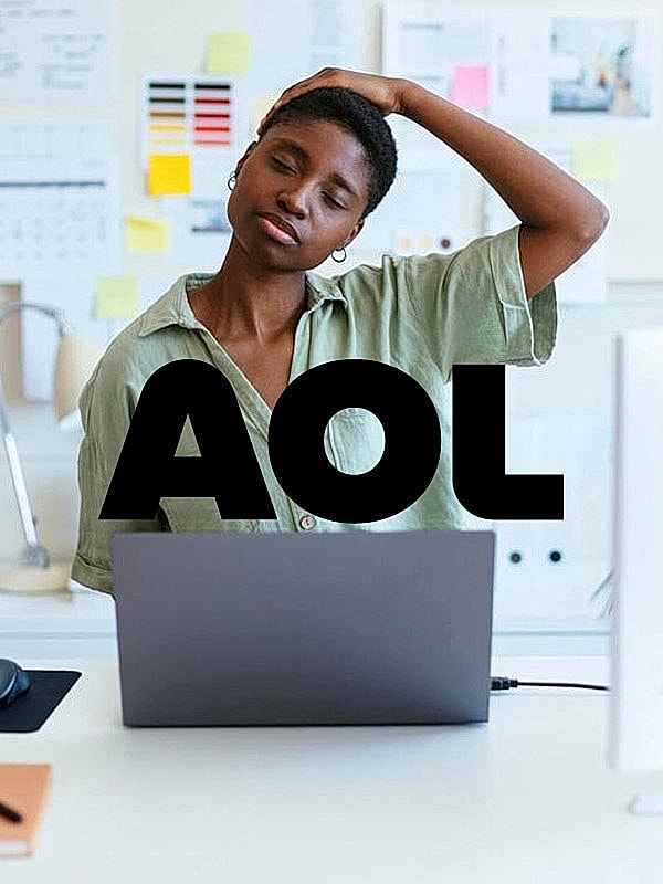 Person stretching at desk with laptop nearby.