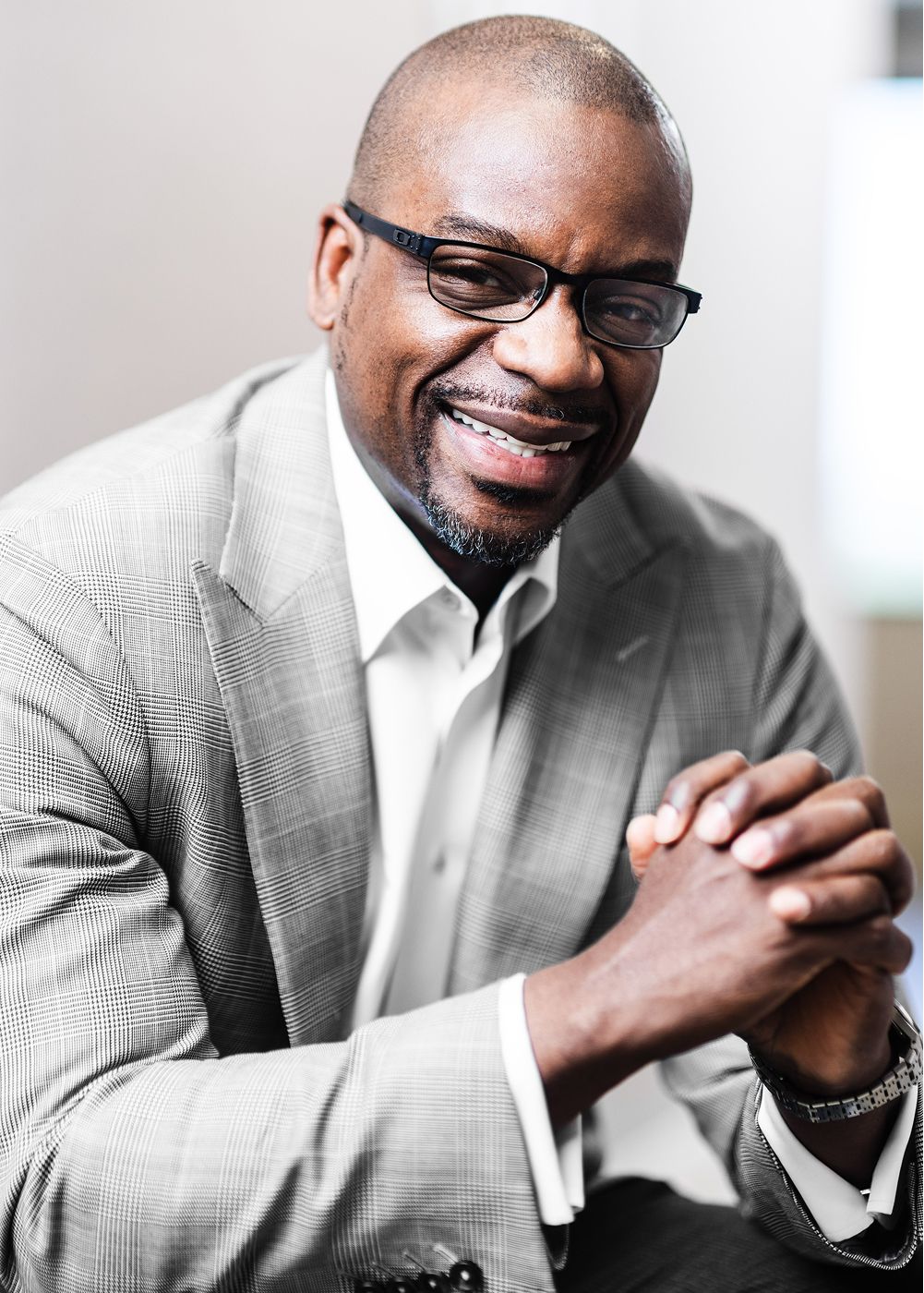 Smiling man in glasses wearing a stylish suit.