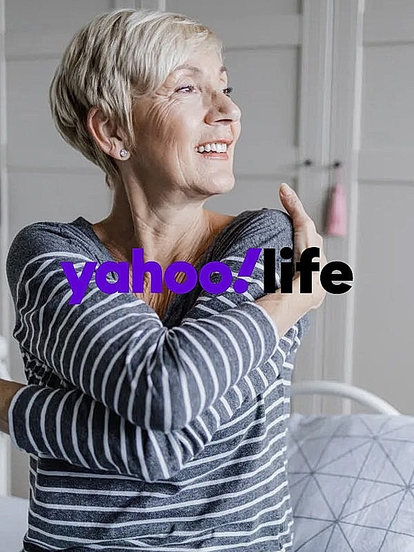 Smiling woman hugging herself in cozy setting