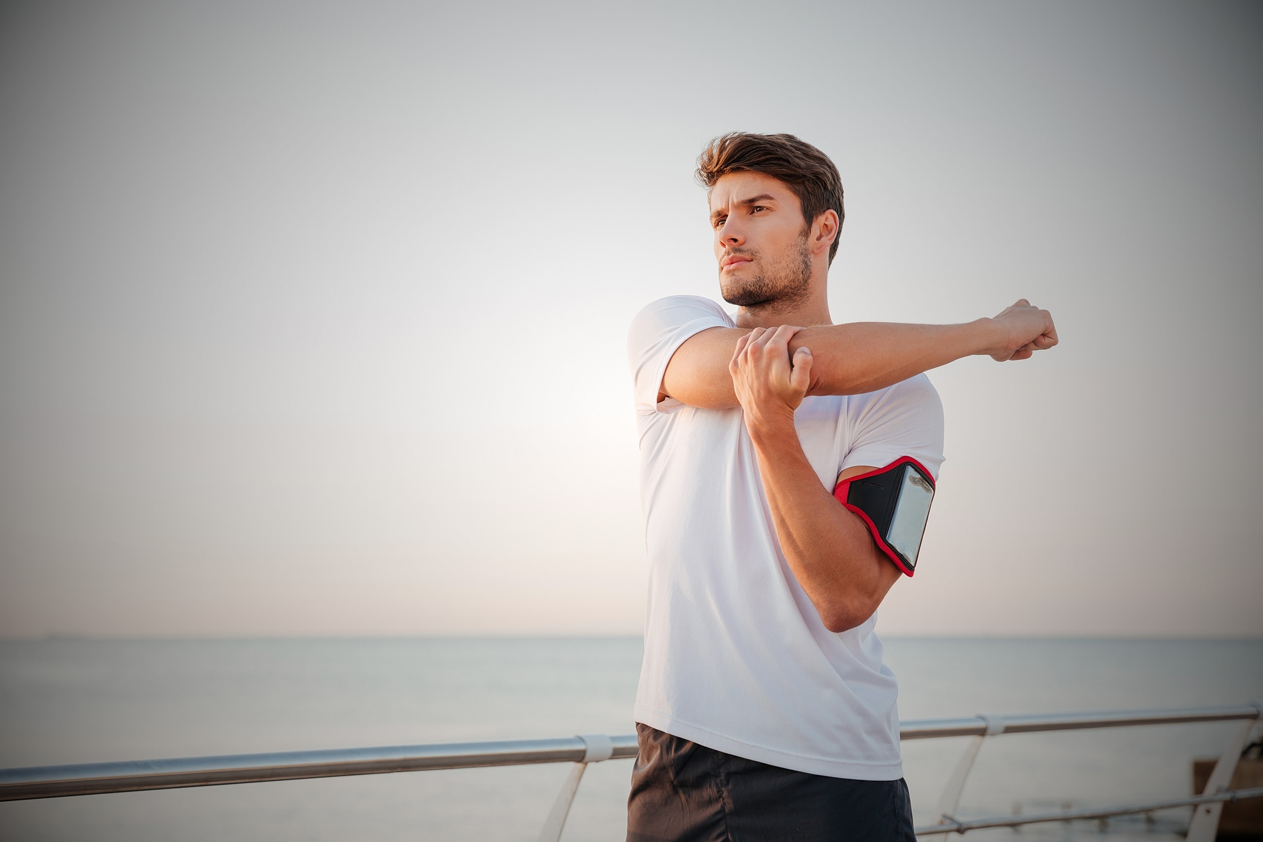 Man stretching by the seaside during sunset.